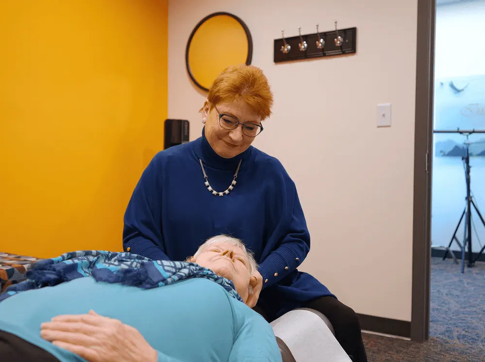 Dr. Trish Wolff treating a relaxed senior patient's neck