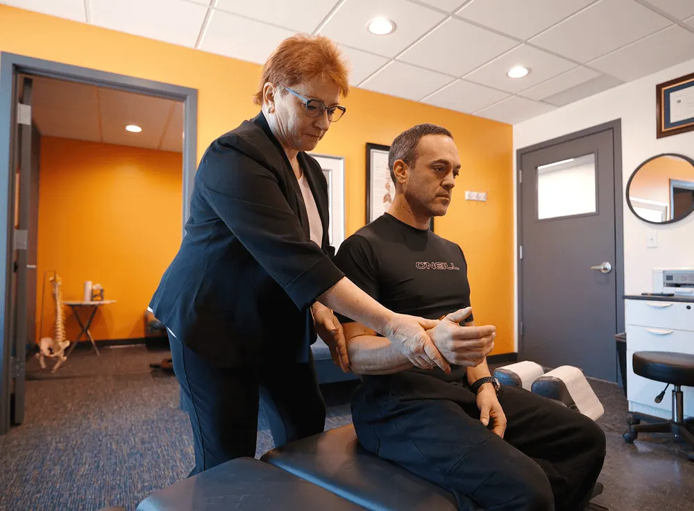 Dr. Trish Wolff adjusting a seated patient's shoulder