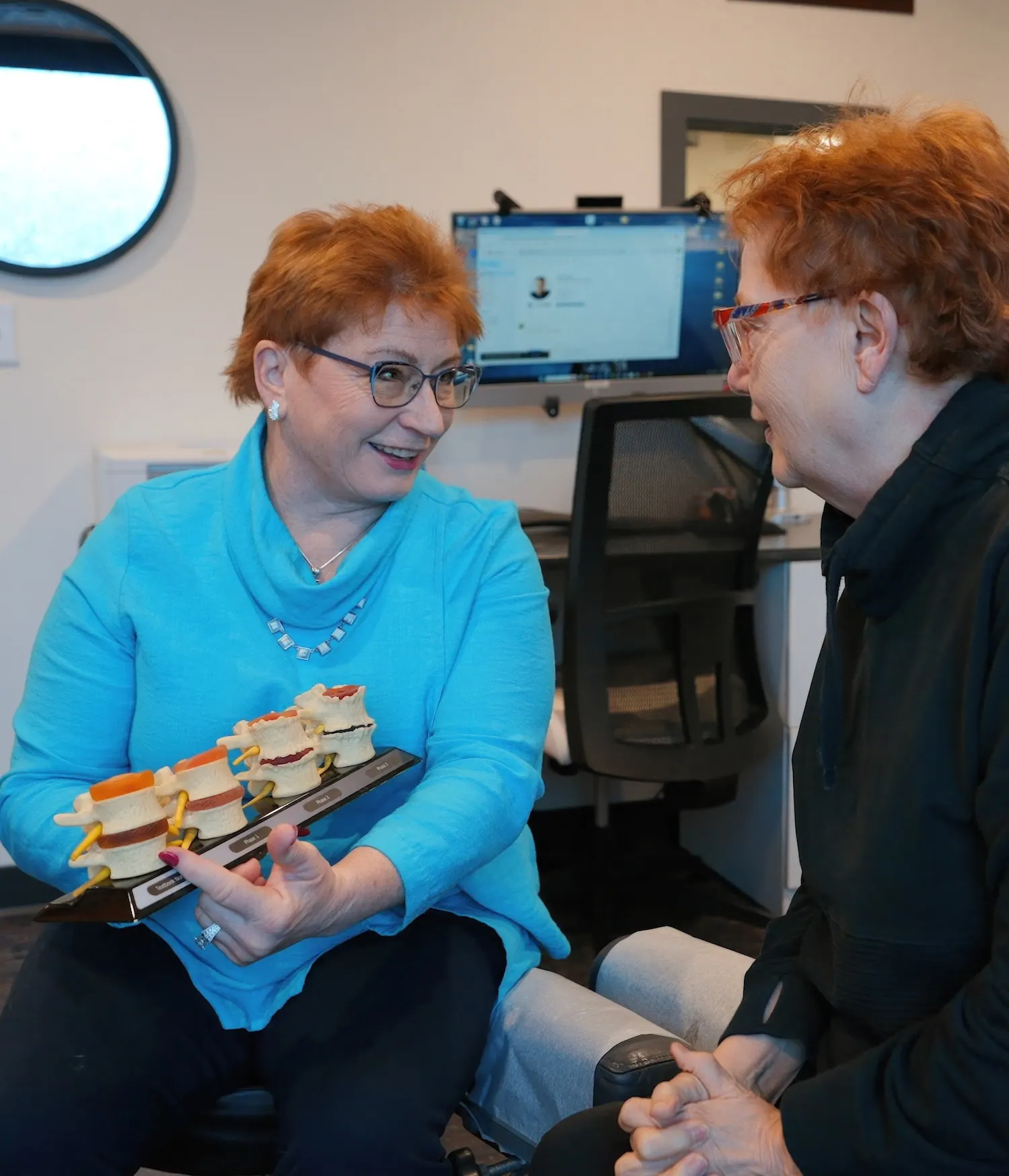 Dr. Trish Wolff holding a vertebrae model while talking with a patient